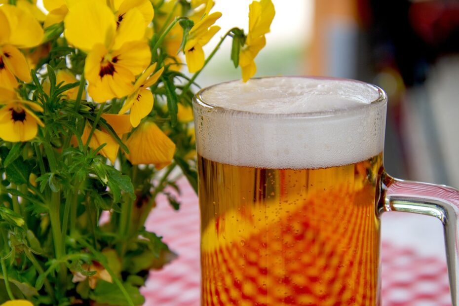 Bier im Glas neben einem gelben Blumenstrauß